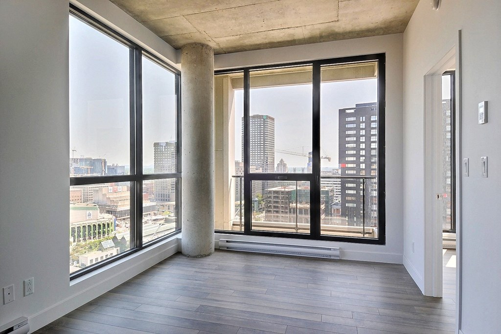an empty living room with large windows and a city view