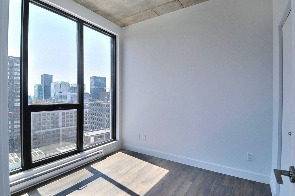 an empty living room with large windows and a city view