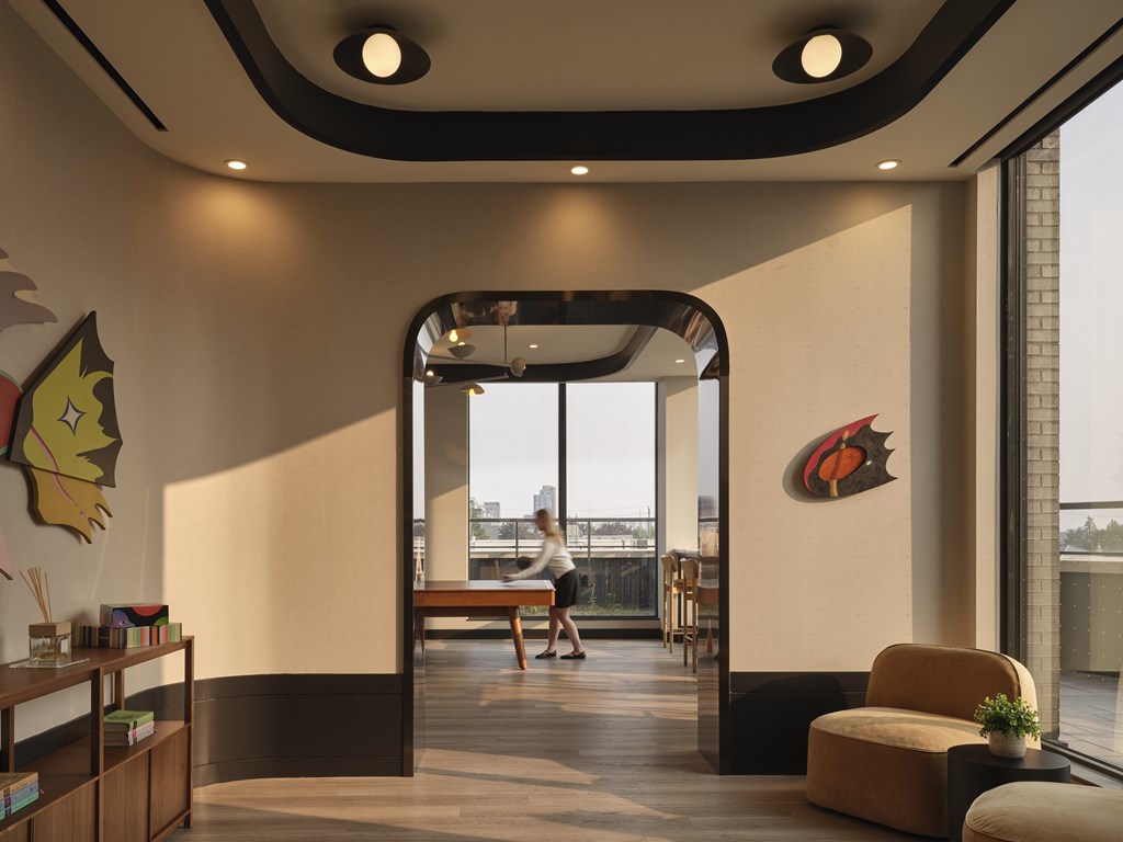 A woman is sitting on a bench in a room with a large window.