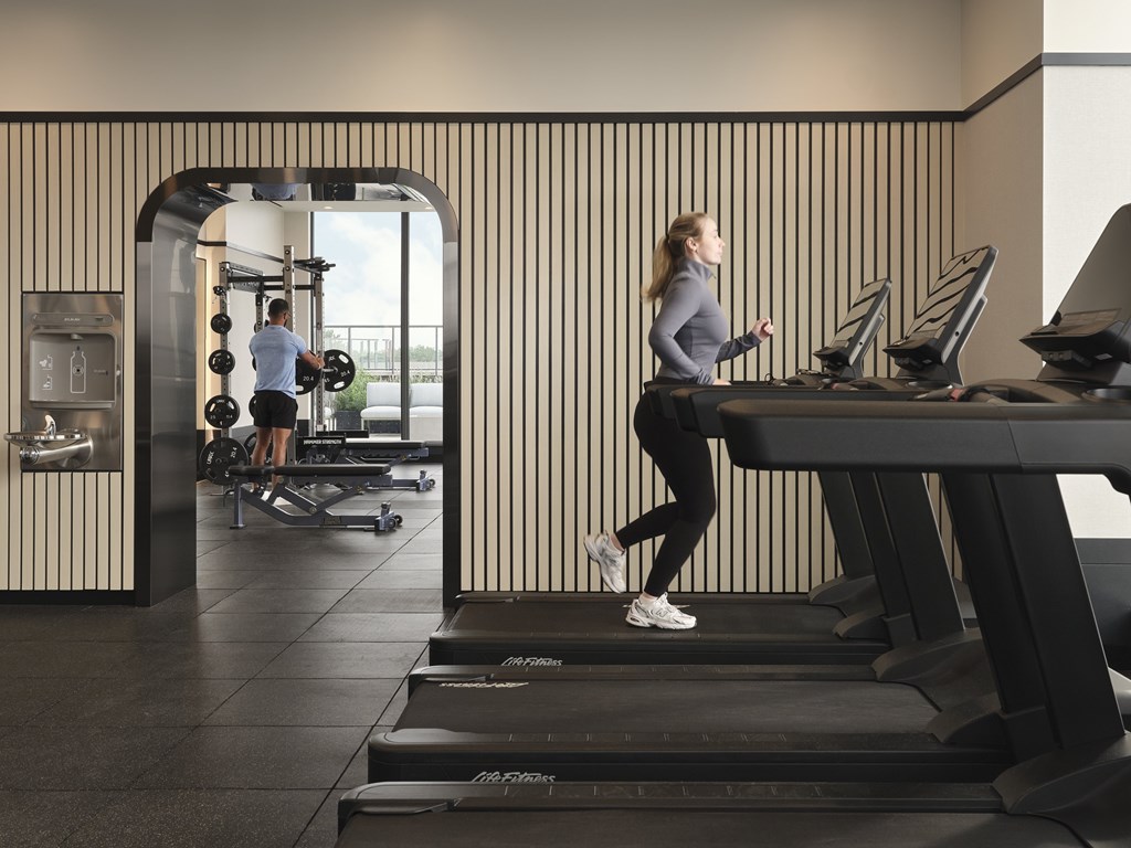 A woman is running on a treadmill in a gym.