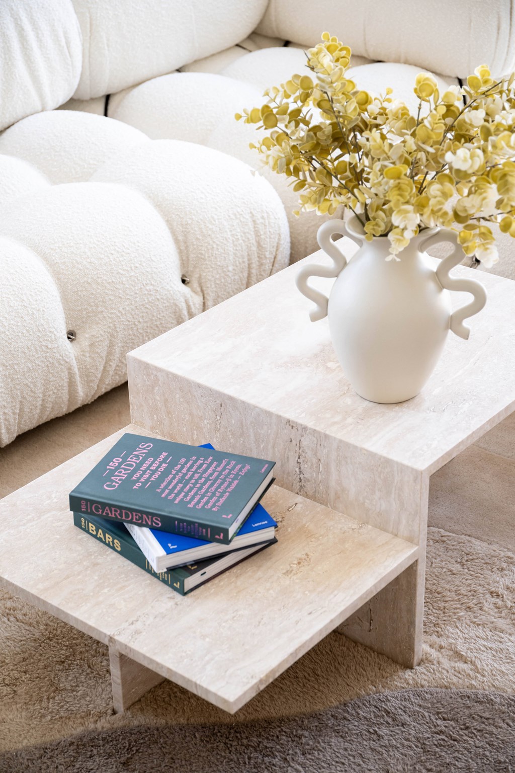 a coffee table with a white vase and books on it