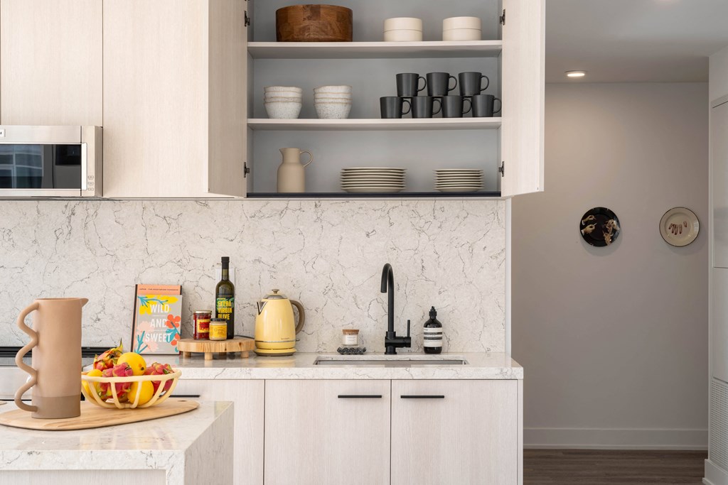 a kitchen with white cabinets and a sink and a bowl of fruit