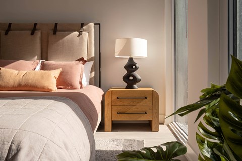 a bedroom with a bed with pink pillows and a nightstand with a lamp