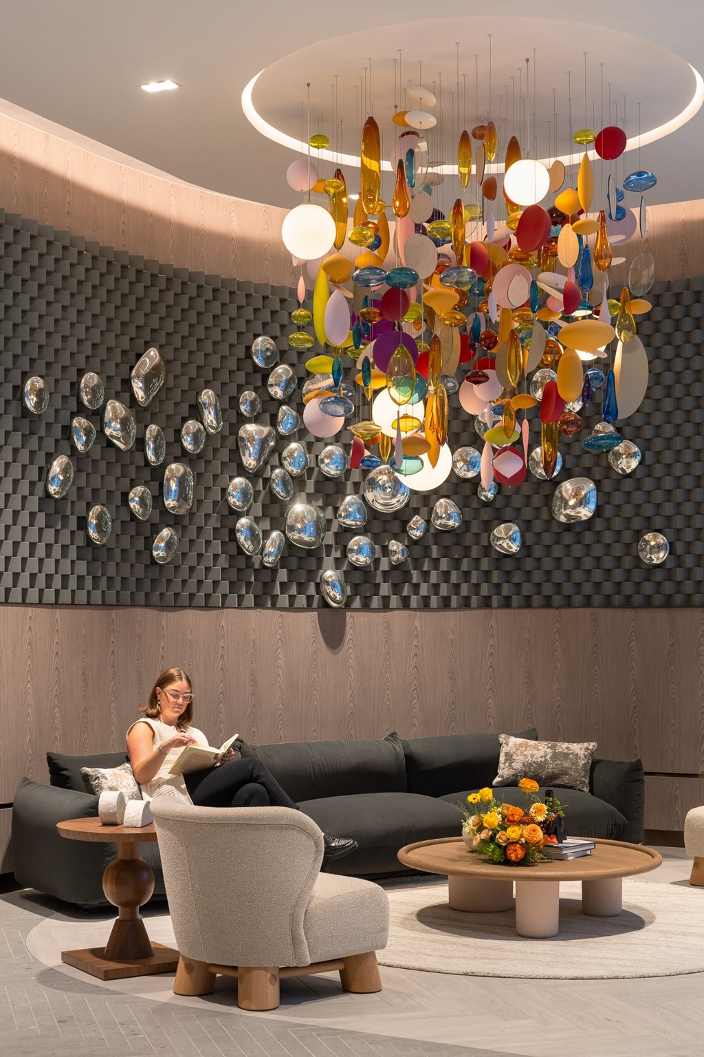 a woman sitting on a couch in a lobby under a glass chandelier