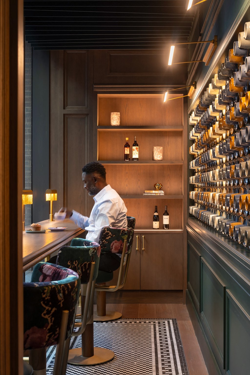 a man sitting at a table in a bar with bottles of wine