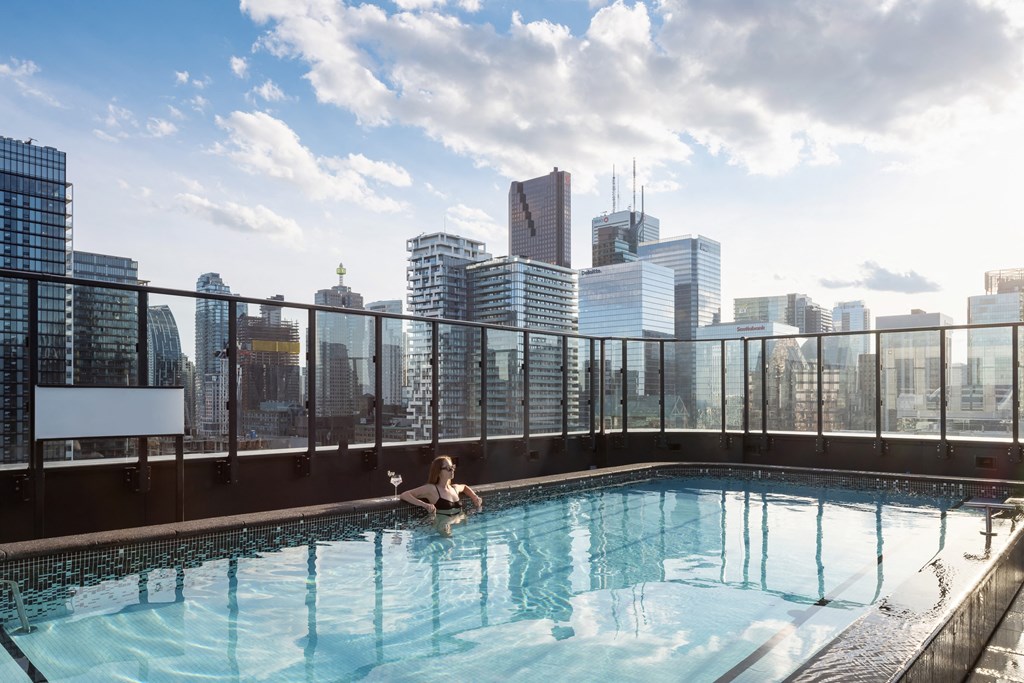 a woman relaxing in a rooftop pool with a view of the city