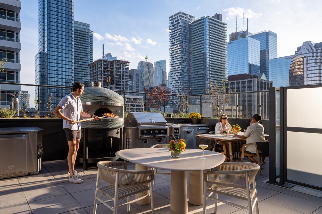 a man is preparing food on a grill on a rooftop terrace with a city