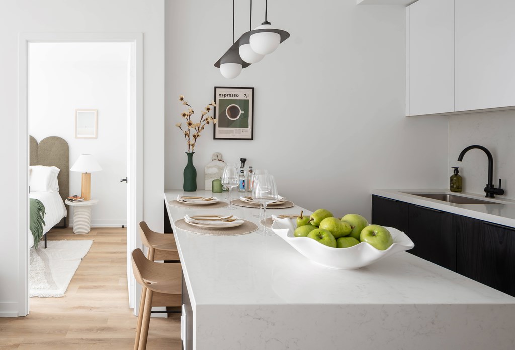 A kitchen with a table set for two and a bowl of green apples.