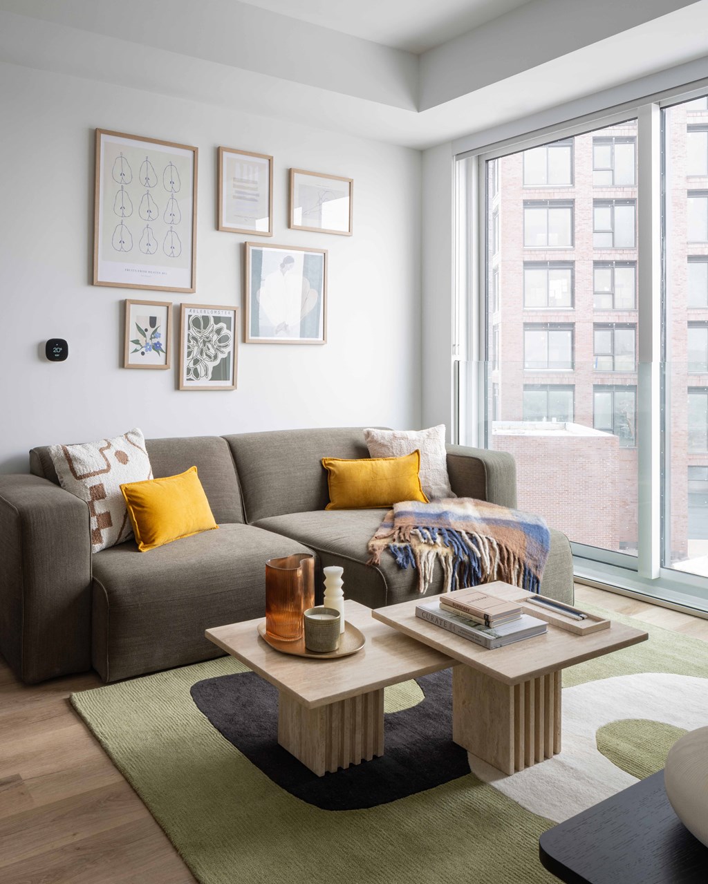 A living room with a grey couch, a coffee table, and a large window.