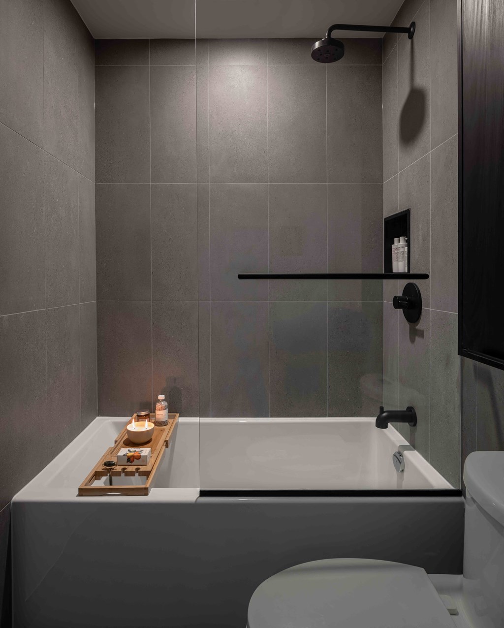 A modern bathroom with a white bathtub and grey walls.