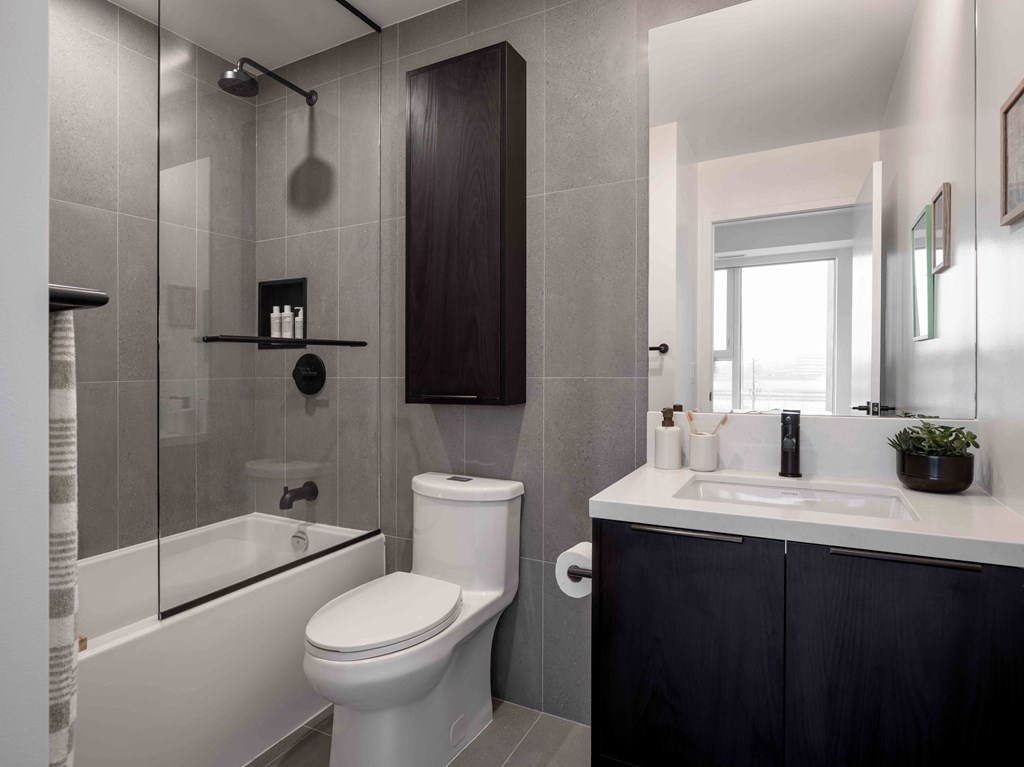 A modern bathroom with a white toilet, a sink, and a shower.