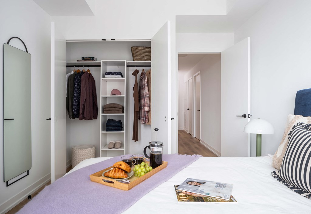 A bedroom with a bed, a tray of food, and a magazine on the bed.