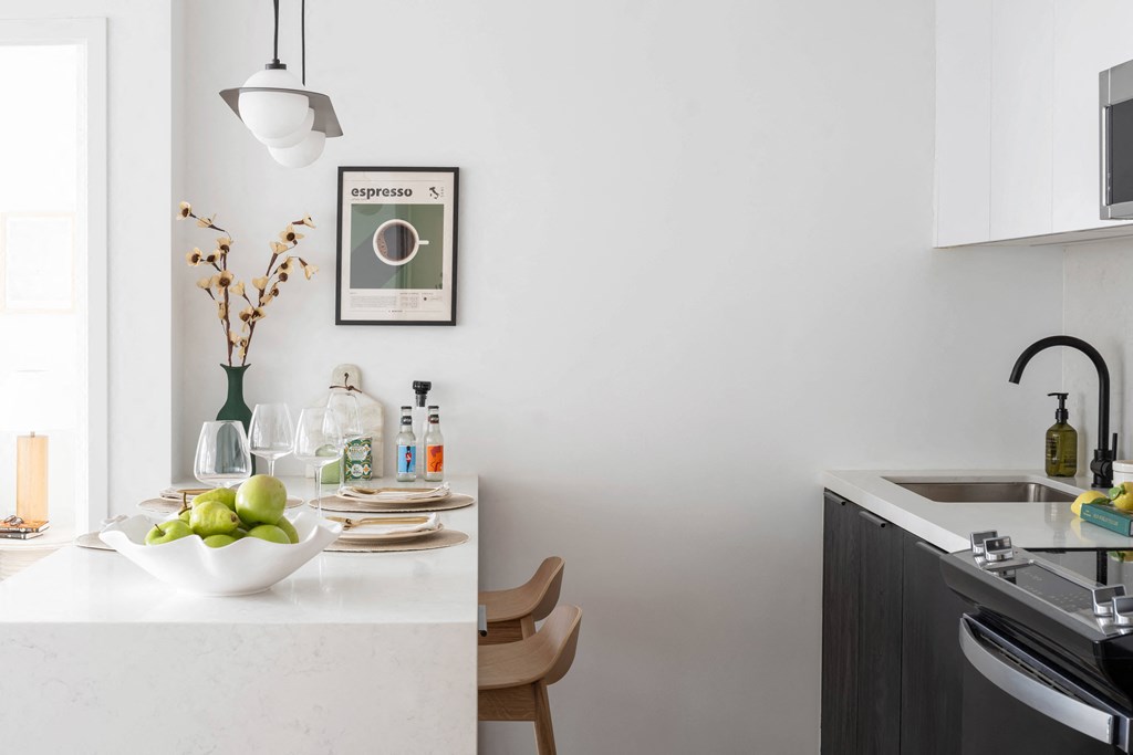 A kitchen with a white countertop and a bowl of green apples on it.