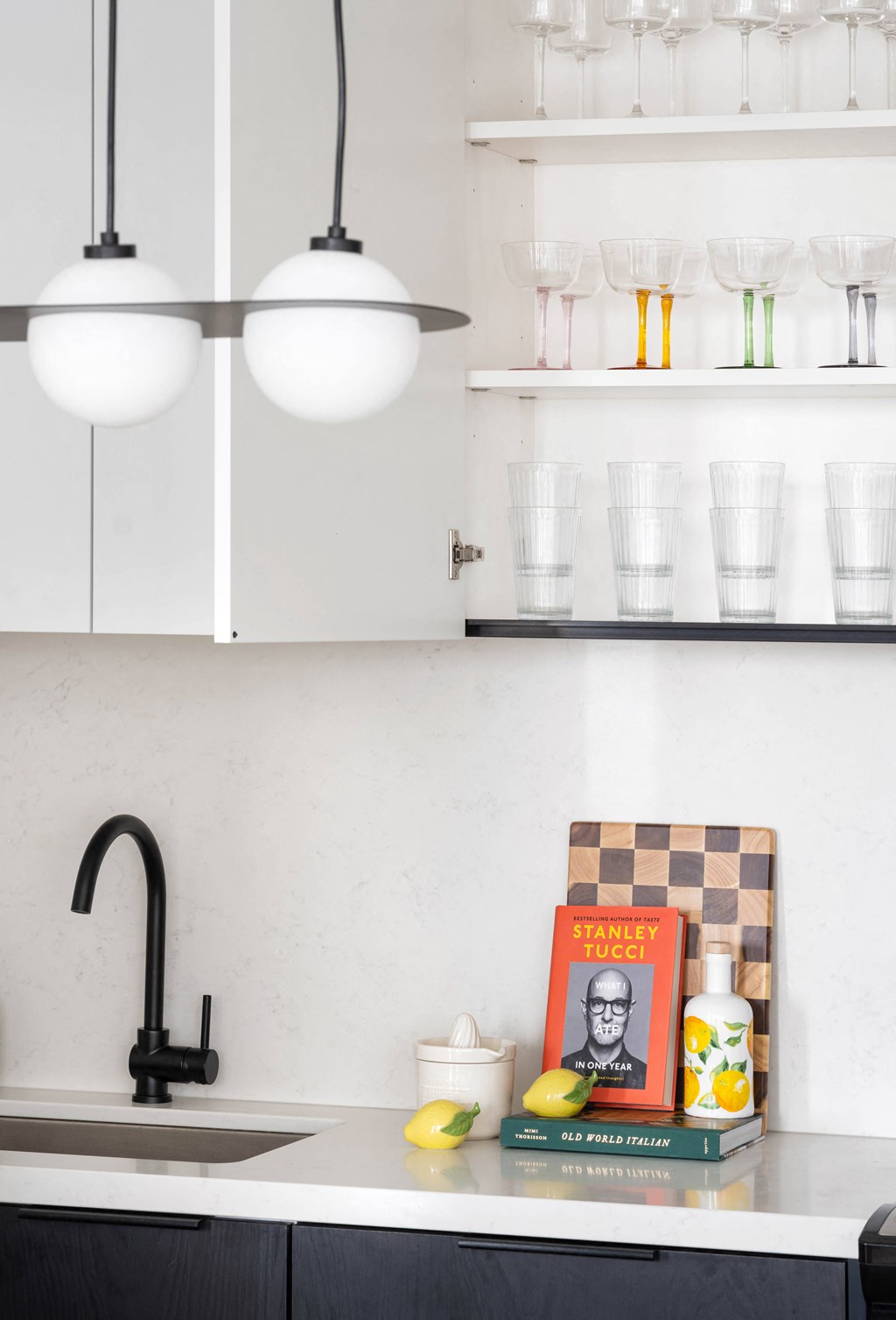 A kitchen with a black faucet and a book about Stanley Tucci.