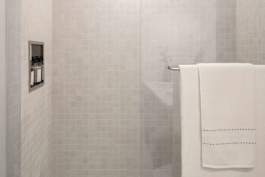 A white towel hangs on a towel rack in a tiled bathroom.