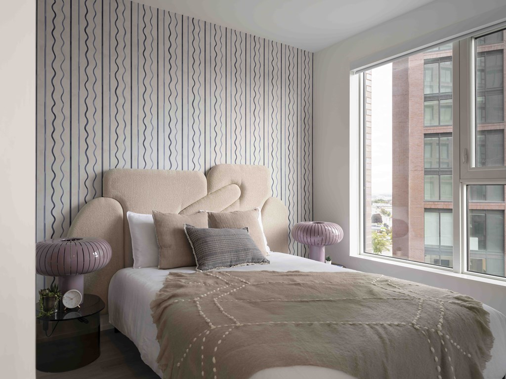 A bedroom with a large bed and a window overlooking a building.