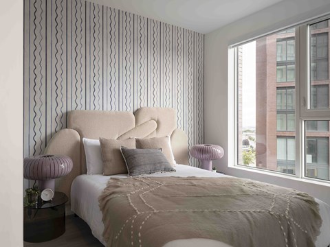 A bedroom with a large bed and a window overlooking a building.