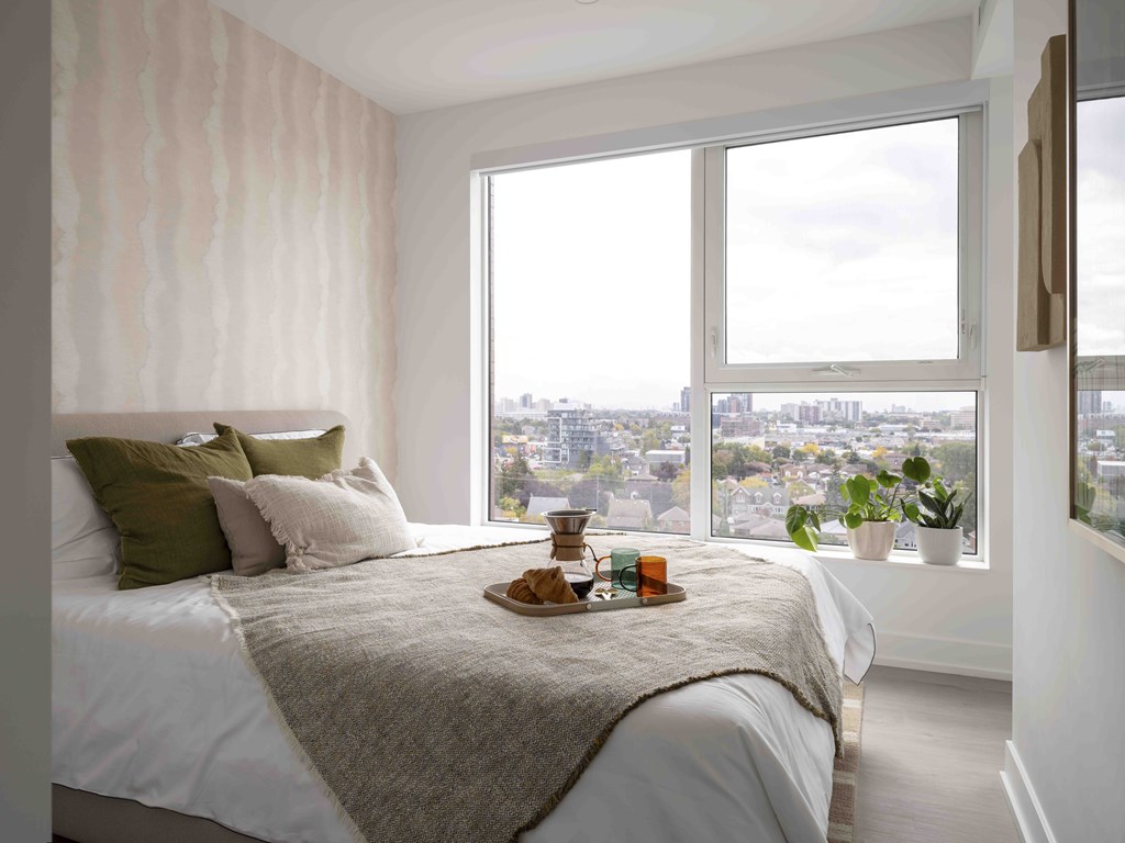 A bedroom with a large bed and a view of the city through the window.