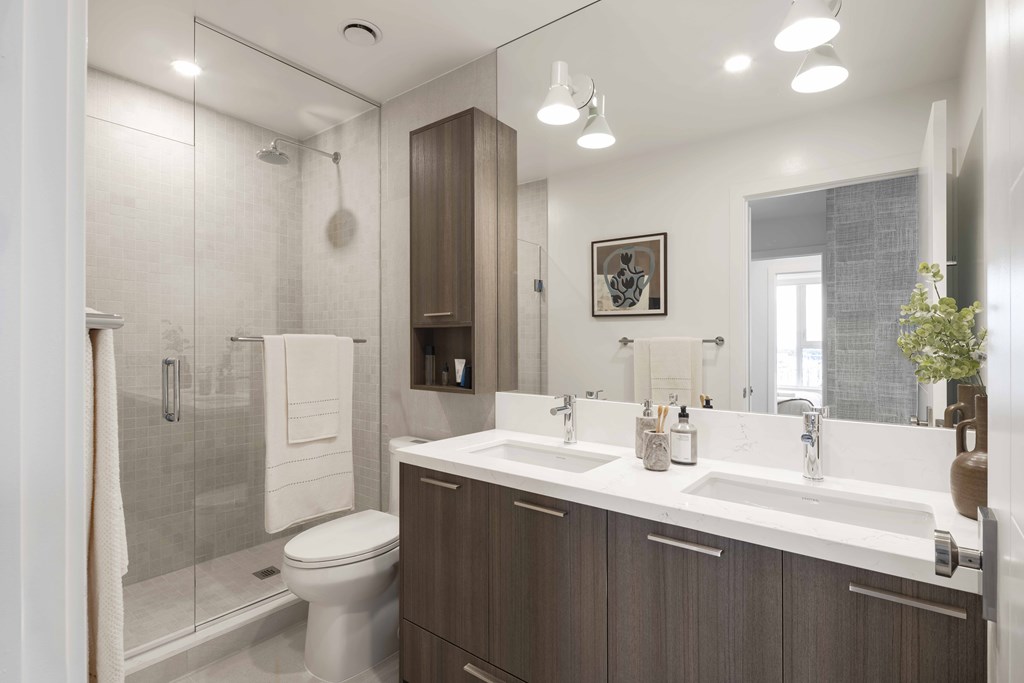A modern bathroom with a walk-in shower and double sinks.