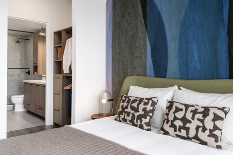A modern bedroom with a large bed and a bathroom area.