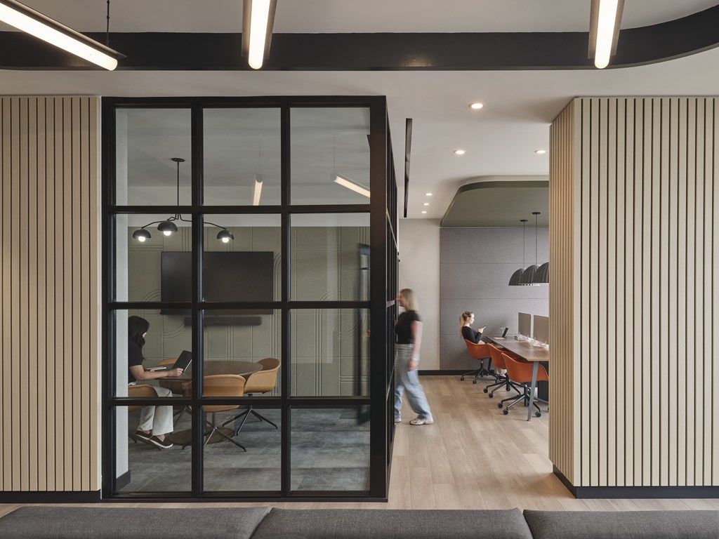A modern office space with a person working on a laptop.