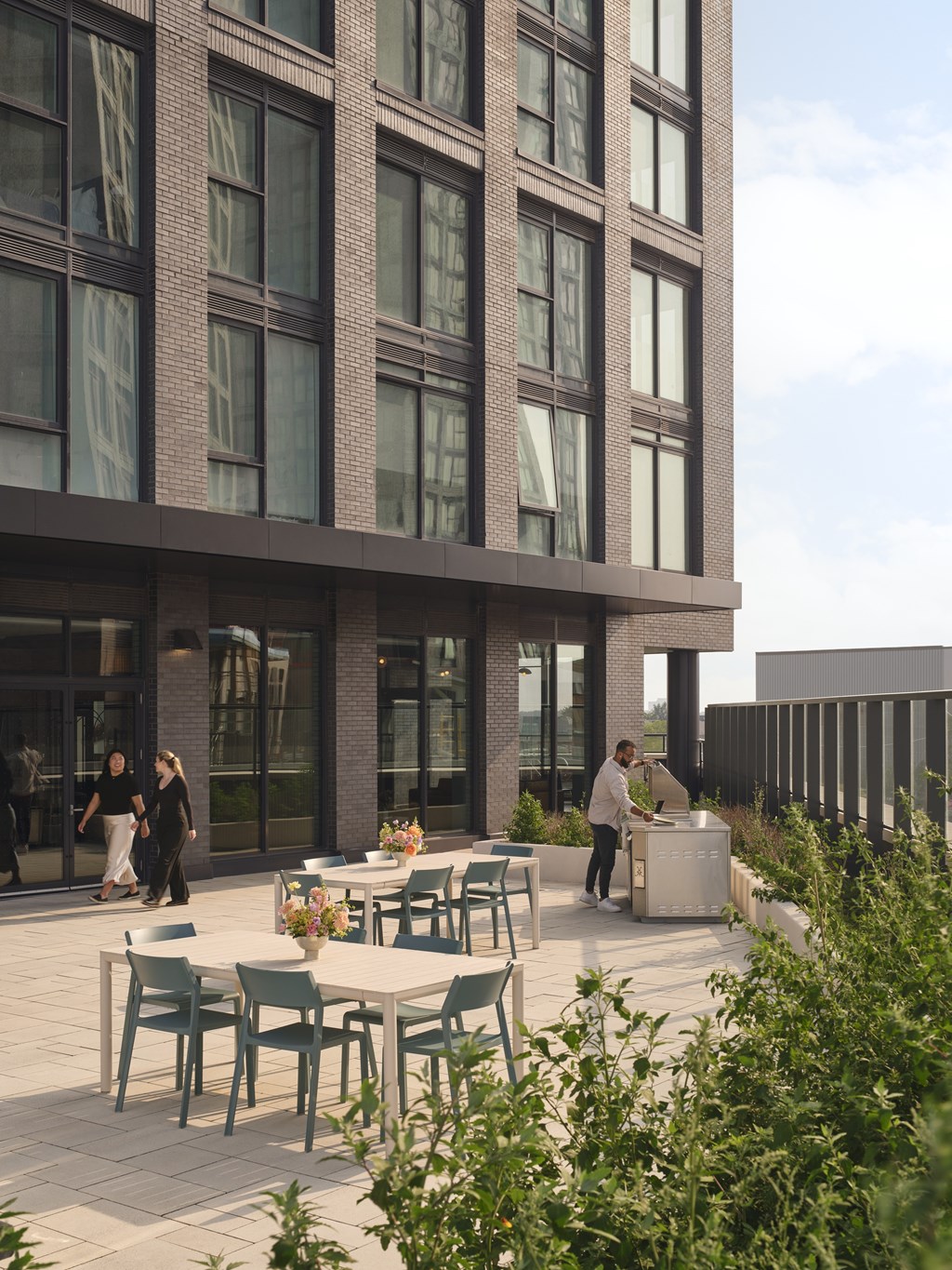 A modern building with a patio and people walking around.