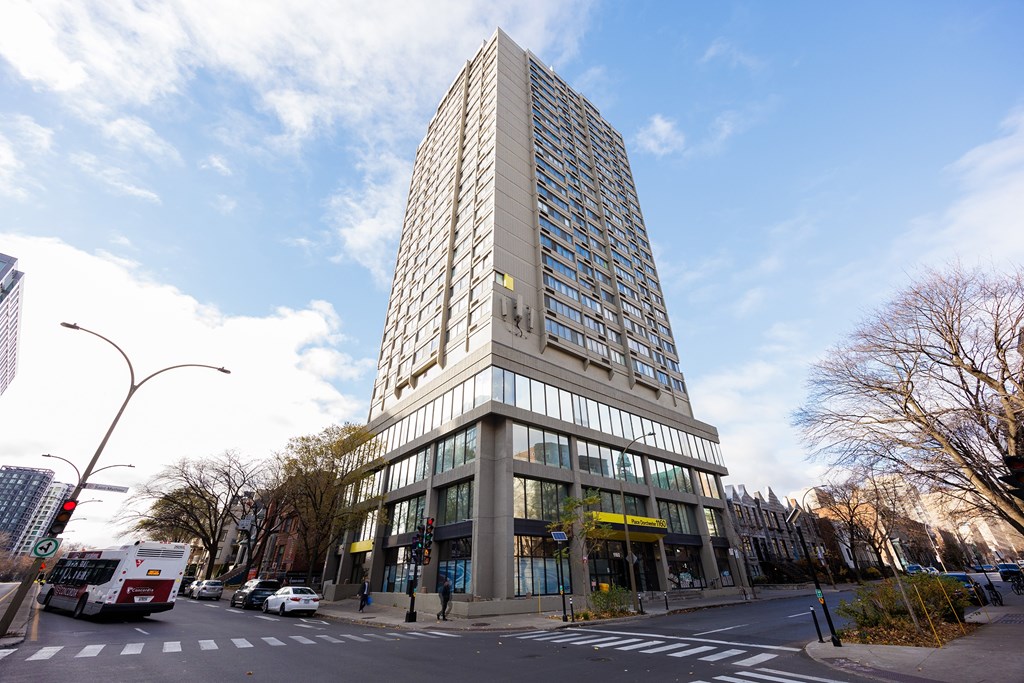 A tall building with many windows is in the middle of a street.
