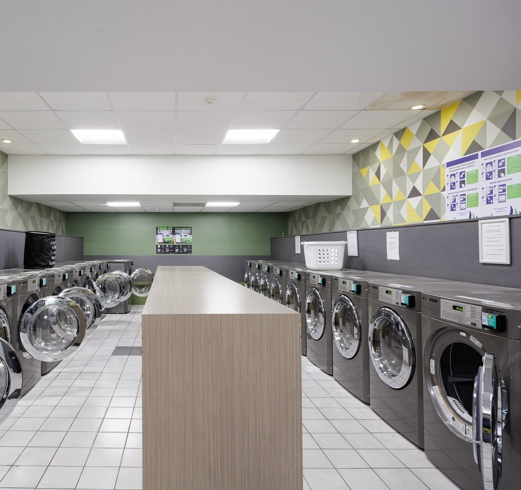 A laundromat with rows of washing machines and a wooden counter in the foreground.