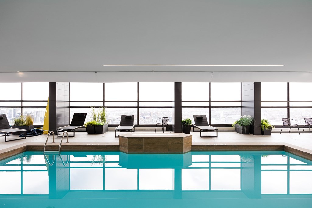A large indoor swimming pool with a hot tub and lounge chairs.