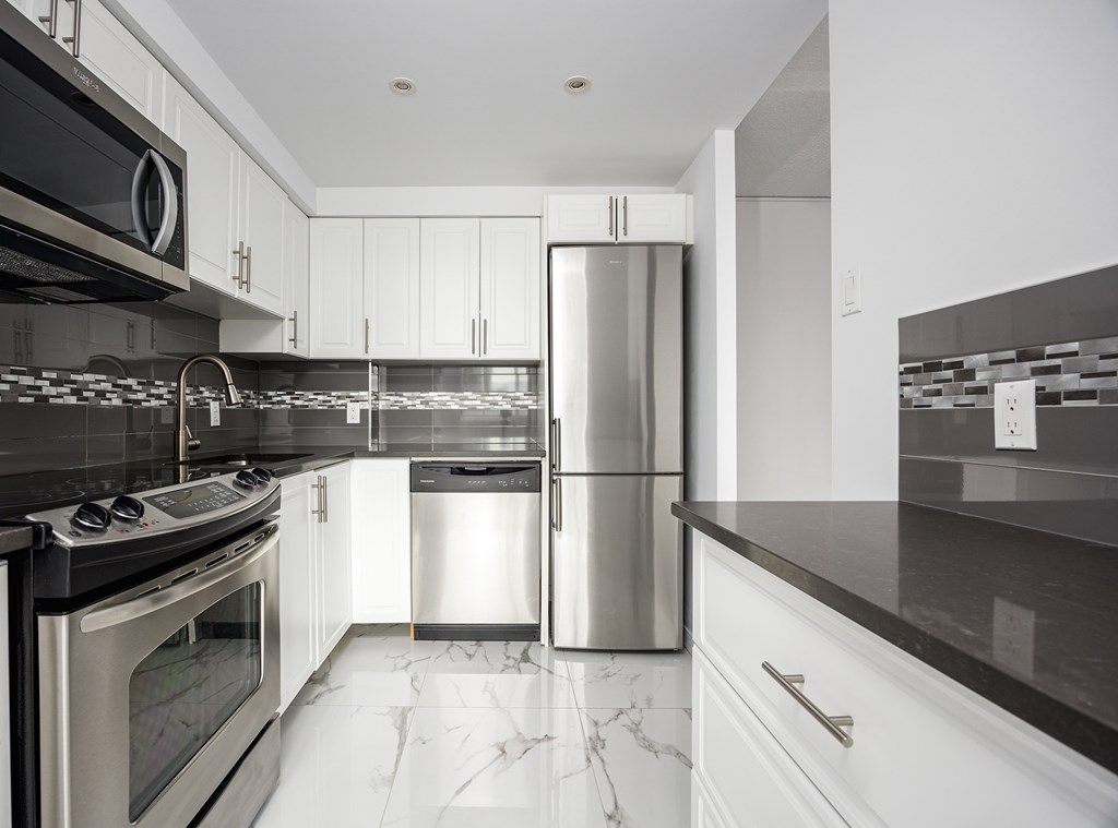 A modern kitchen with stainless steel appliances and white cabinets.