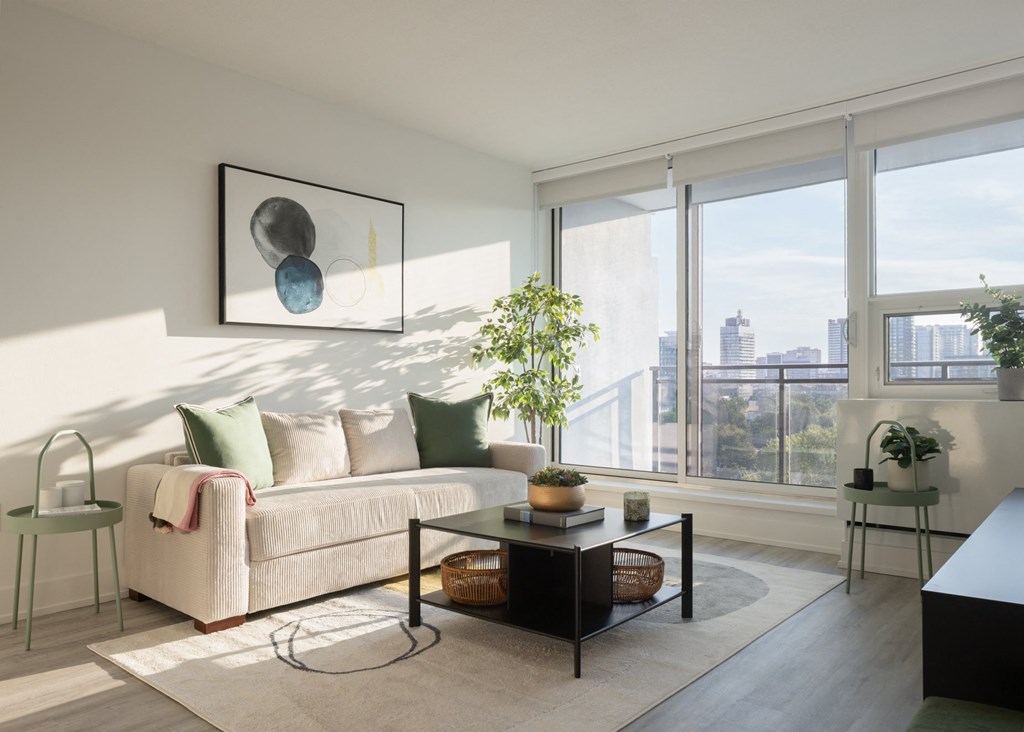 a living room with a beige couch and a coffee table and a large window