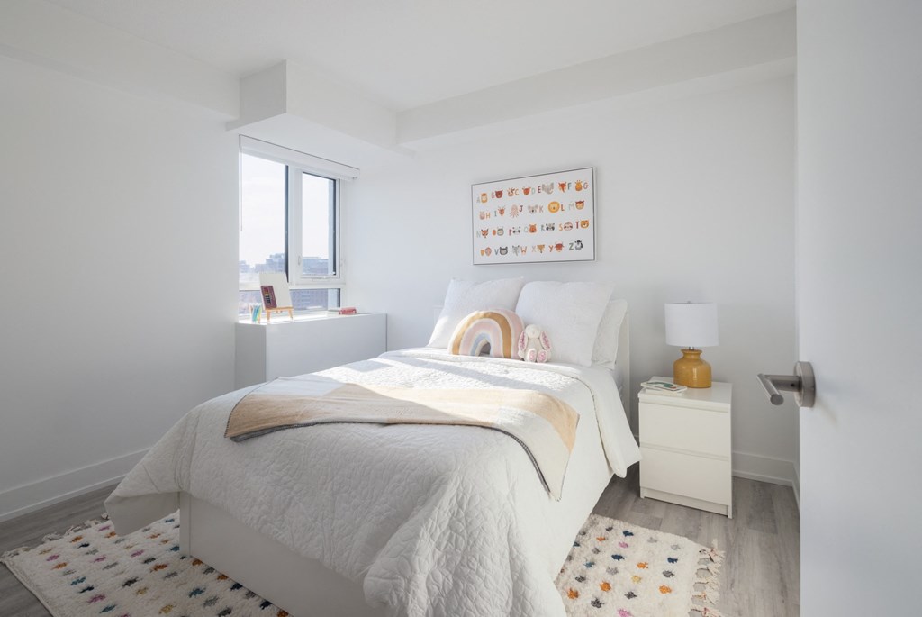 a white bedroom with a bed and a window