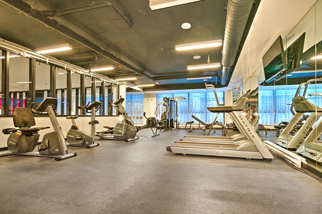 a gym with cardio equipment and weights on the floor