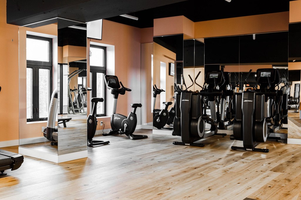 a gym with cardio machines and weights on a wooden floor