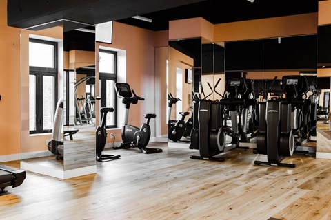 a gym with exercise machines and weights on a wooden floor