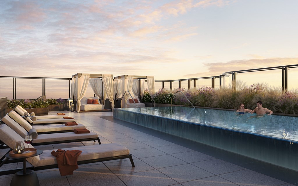 a group of people swimming in a pool on a rooftop overlooking the ocean