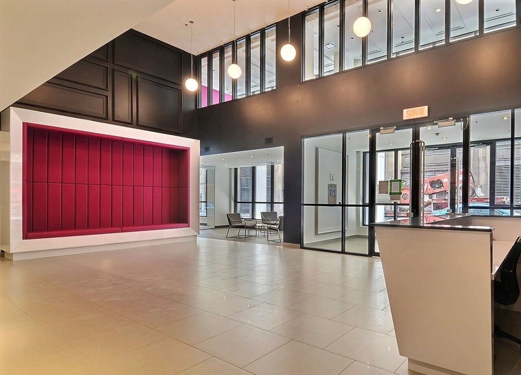 A large open space with a red wall and a white reception desk.