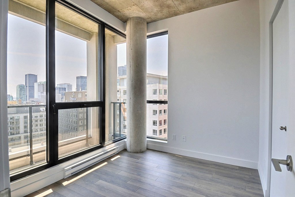 an empty living room with large windows and a city view