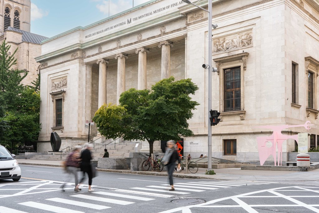 people crossing the street in front of a large building