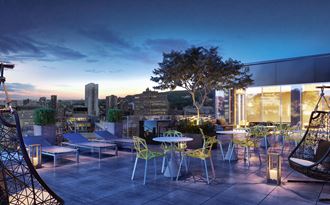 a rooftop terrace with tables and chairs and a city at dusk
