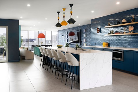 A modern kitchen with a long white island and bar stools.