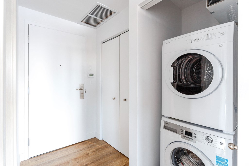 a washer and dryer in a laundry room with white walls and wood floors