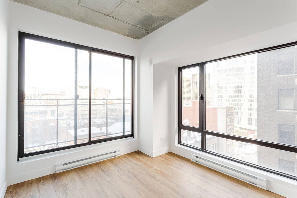 a living room with large windows and wood floors and a city view