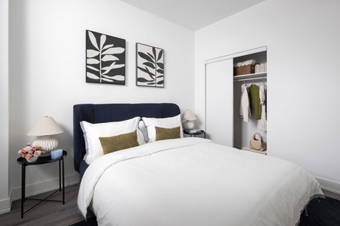 A bedroom with a large bed and a nightstand with a lamp.