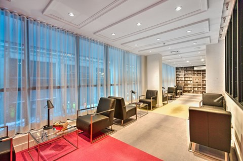 A waiting room with a red carpet and black chairs.