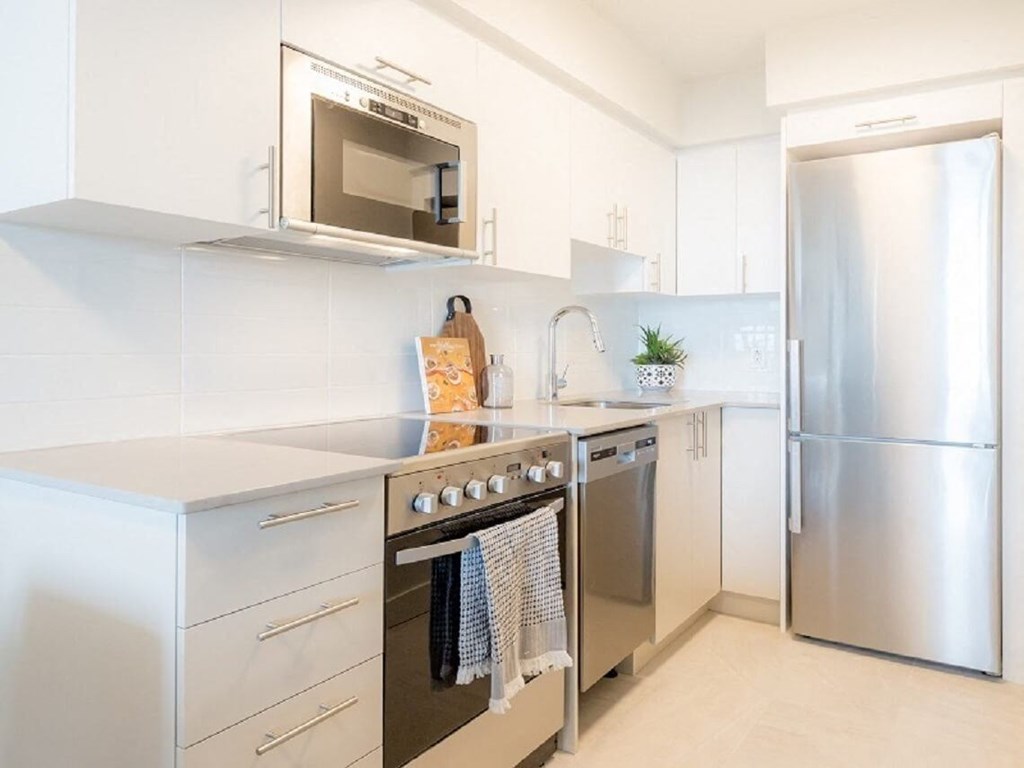 a modern kitchen with stainless steel appliances and white cabinets