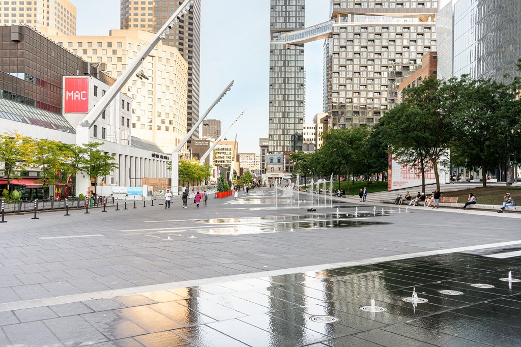 a city square with water fountains and tall buildings