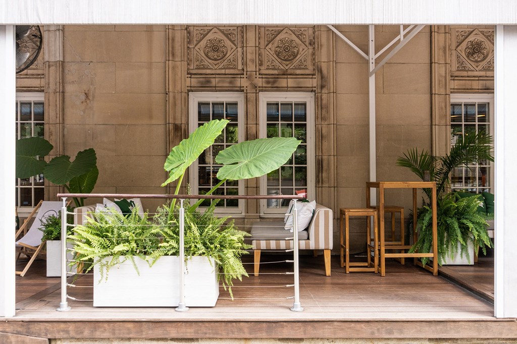 a terrace with chairs and potted plants in front of a building