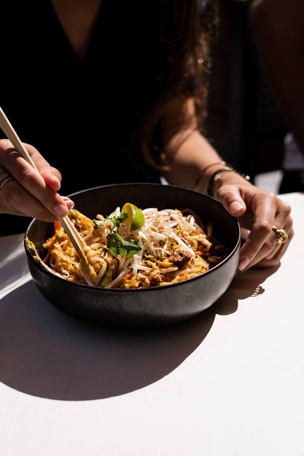 a woman eating a bowl of noodles with chopsticks