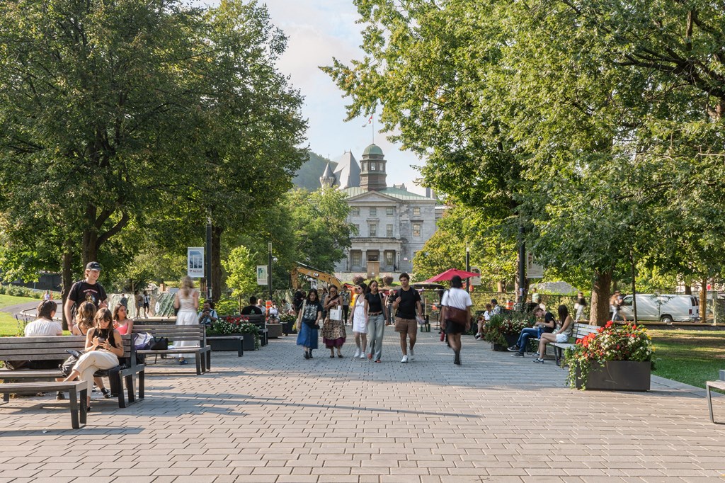 people walking and sitting on benches in a park